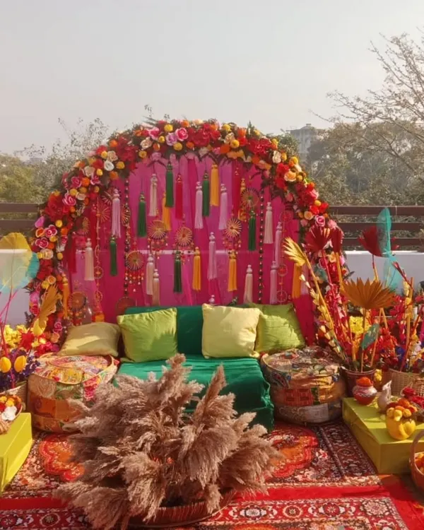 A perfect rooftop Mehandi setup with a vibrant, bohemian vibe. We used a floral arch, colourful tassels, low seating with gaddas, and lots of props for a festive and photogenic event.