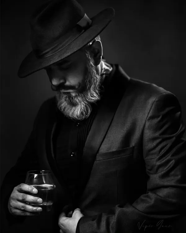 This black and white portrait uses a classic lighting technique to create a moody, cinematic feel. The fedora and suit add to the character, making it a strong addition to any actor's portfolio.