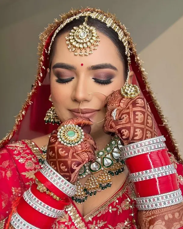 My pretty bride with her eyes closed, showing off the beautiful smokey brown eyeshadow. Her look is complete with a traditional matha patti and nath.