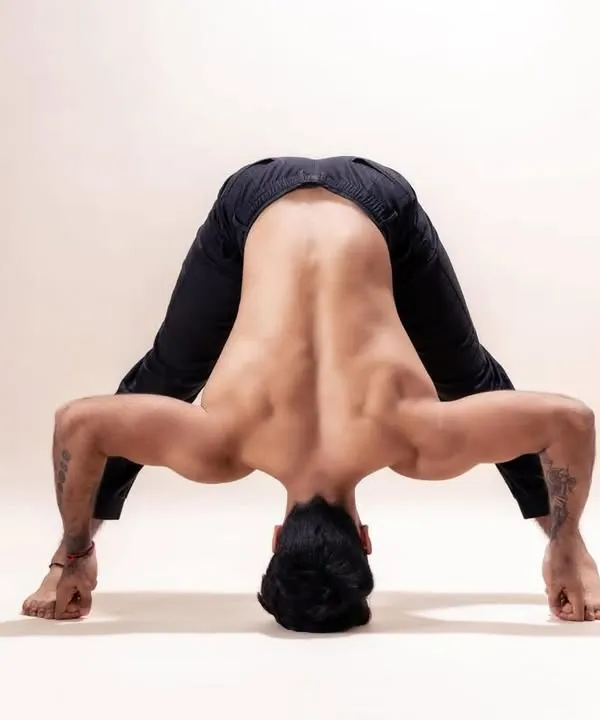 This is a deep forward fold within Prasarita Padottanasana (Wide-Legged Standing Forward Bend). Mastering such poses teaches students about leverage, hamstring flexibility, and spinal release, all of which are key anatomical lessons in our course.
