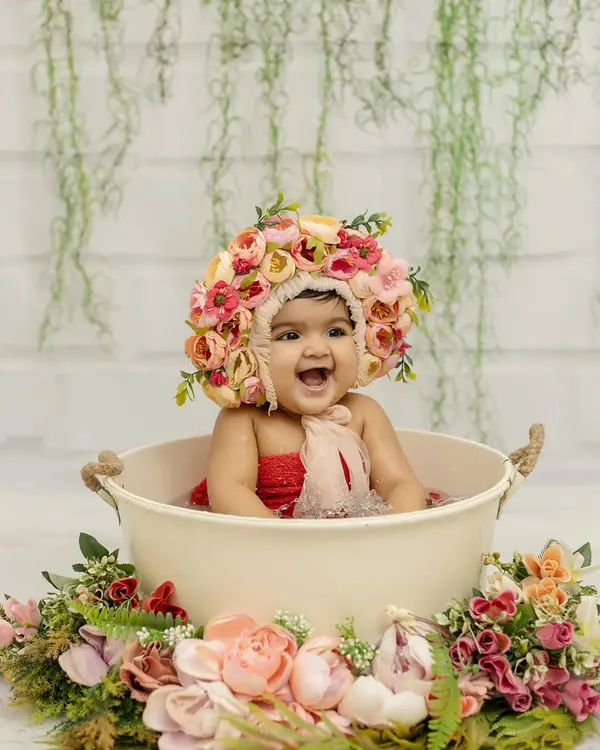Cuteness overloaded! A six-month-old baby girl having a blast in a bathtub splash session, complete with a beautiful floral bonnet.