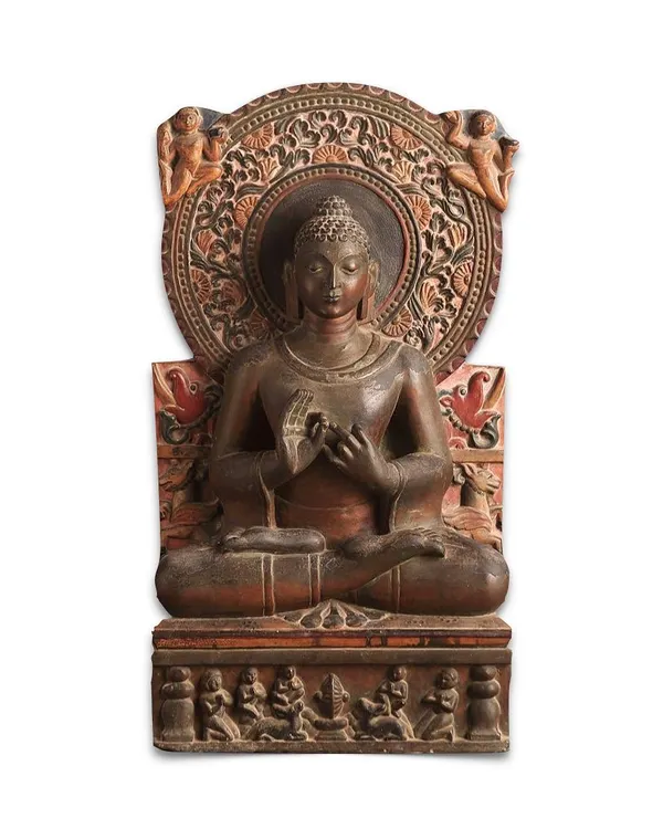 A magnificent 8th-century stone stele of Gautam Buddha from North India. The Buddha is depicted in 'dhyanasana' with his hands in the 'dharmachakra' mudra, seated on a throne with intricate carvings of worshippers and animals.