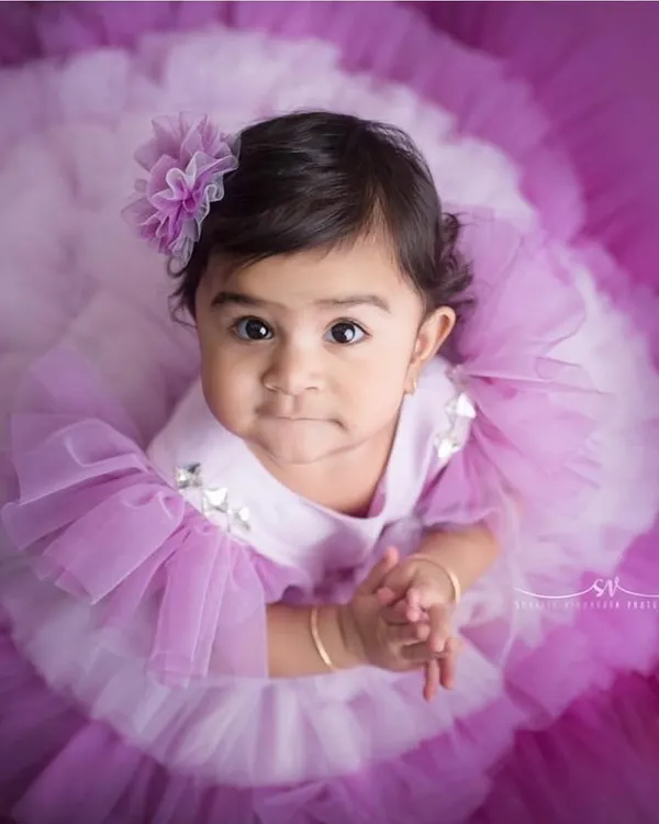 This little one came to slay. This custom lavender gown with its dramatic ruffled tulle skirt and matching floral hairpiece is designed for maximum impact, ensuring your baby is the center of attention at her milestone celebration.
