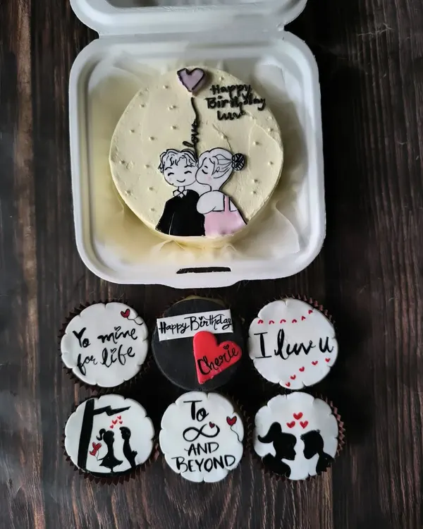 A romantic combo featuring a hand-painted bento cake of a couple's sweet moment, paired with cupcakes that continue the love story with messages and silhouettes.