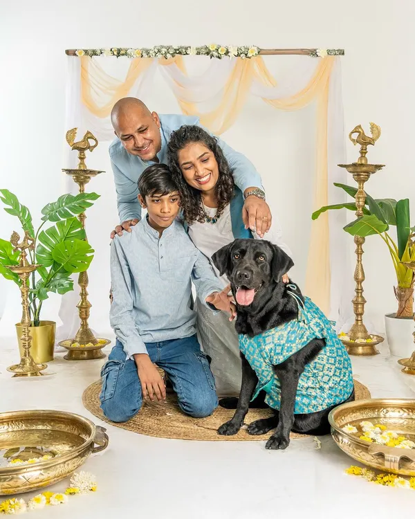 A beautiful family portrait from a Diwali mini-session. The family, dressed in festive attire, gathers around their black Labrador for a perfect holiday photo.