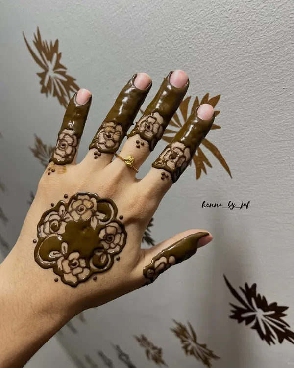 A modern floral design featuring a single large motif on the back of the hand. The fingers are decorated with matching floral bands, creating a bold yet uncluttered look.