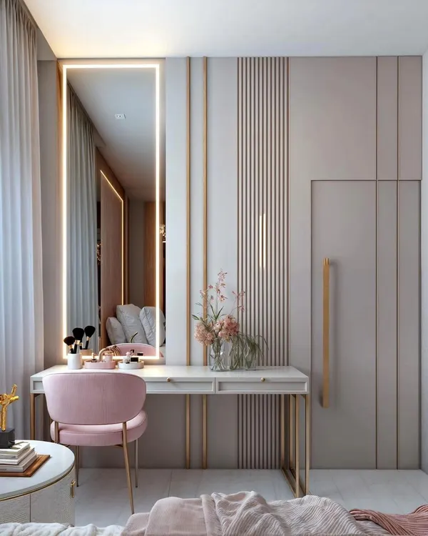 A chic and elegant vanity corner with a sleek desk, a full-length mirror with integrated lighting, and a plush pink chair. The design is seamlessly integrated with the wardrobe.