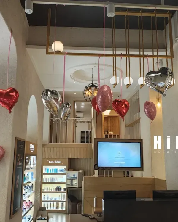 This wide shot shows how the Valentine's Day balloon decorations filled the entire two-story salon space. The hanging hearts add a festive touch without taking up any floor space, making it perfect for a busy commercial environment.