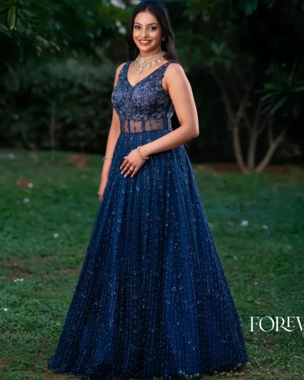 This full-length view showcases the dazzling effect of the blue katdana corset gown. The intricate beadwork covers the entire gown, creating a sparkling texture that catches the light beautifully, perfect for a reception or gala.
