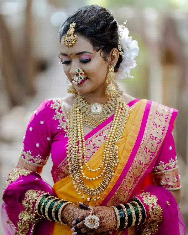 A classic Maharashtrian bridal portrait. We created a look that highlights her beautiful features, complete with traditional gold jewelry, a floral bun, and the iconic crescent bindi.