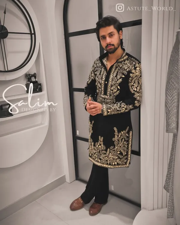 A client wearing a black velvet kurta with heavy gold and silver floral embroidery. This is a luxurious and statement-making piece, perfect for a grand celebration or reception.