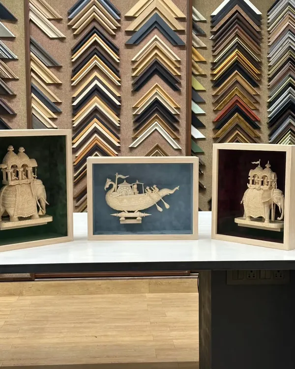 A look at the completed Sholapith art pieces, each in its own custom shadow box. The light maple wood frames and distinct suede backgrounds were chosen to complement the individual character of the boat and elephant sculptures.