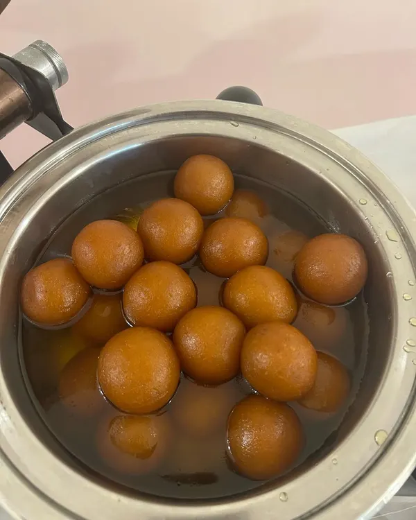 A pot of warm, syrupy Gulab Jamuns. This classic Indian dessert is a sweet and satisfying end to any meal.
