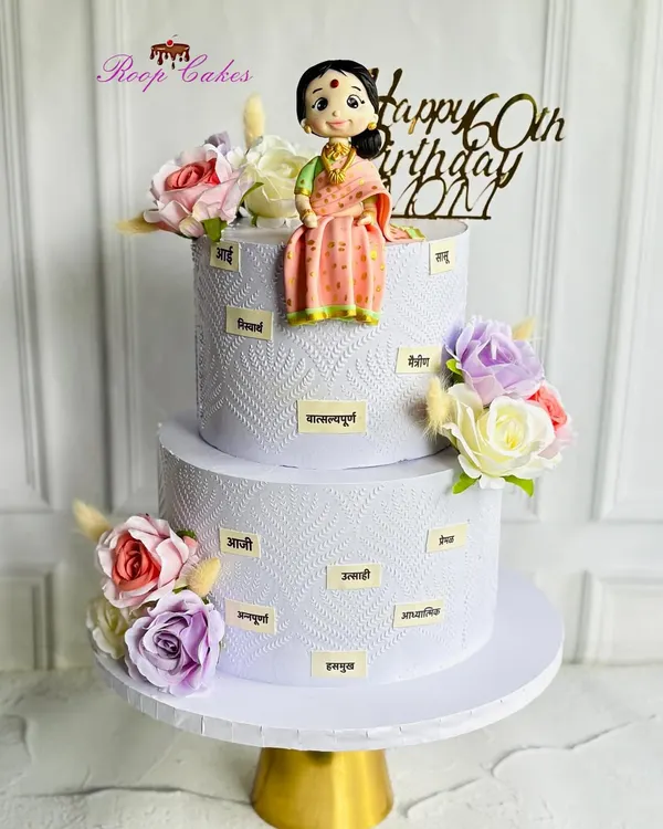 Celebrating 60 graceful years with this custom two-tier cake. It features a beautiful fondant figurine of a mother in a traditional saree, surrounded by words that describe her loving nature.