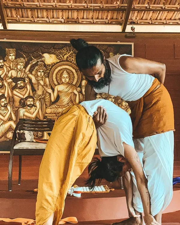 True progress in yoga comes from discipline and patient guidance. I am assisting a student in a deep forward bend, helping them find their edge safely while respecting the body's limits.