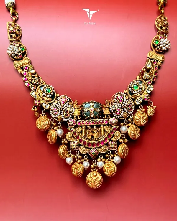 This temple style gold necklace is a tribute to tradition. It features intricate nakshi craftsmanship, uncut diamonds, pearls, and rich enamel detailing, making it a perfect heirloom for the modern woman who cherishes her roots.