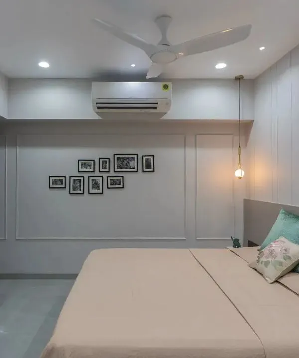 This serene bedroom uses a soft, muted color palette to create a tranquil atmosphere. The wall molding and gallery of family photos add a personal and classic touch.