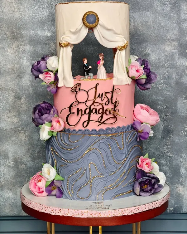 A full view of the "Just Engaged" cake, showcasing its three distinct tiers. From the lit-up proposal scene to the custom acrylic topper and detailed buttercream textures, every element is designed to tell a love story.
