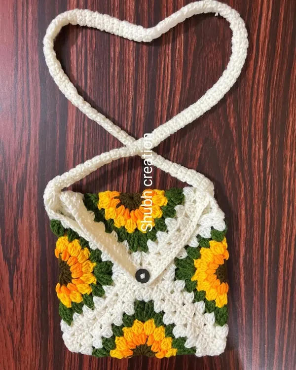 A lovely sunflower-themed granny square sling bag with a simple button closure and a heart-shaped strap, perfect for carrying your essentials.