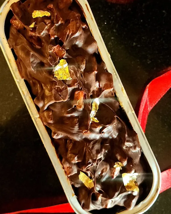 A close up of my vanilla loaf cake, which is soaked with flavor and generously topped with dark chocolate ganache, fresh strawberries, and a touch of edible gold leaf for a little luxury. This is a truly decadent individual dessert.