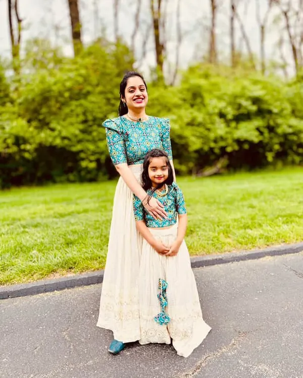 A beautiful moment captured with a mother and daughter in our matching custom lehenga sets. The outfits feature a cream chikankari skirt paired with a vibrant teal printed blouse with puffed sleeves, perfect for family photoshoots and special events.