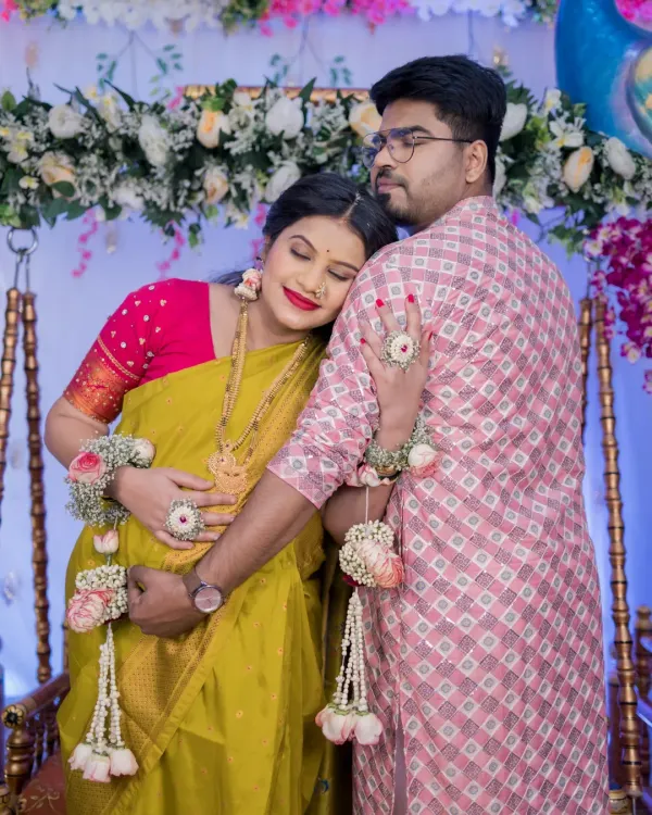A tender moment between an expecting couple during their traditional baby shower. The mother-to-be rests her head on her partner's shoulder, both embracing the baby bump, showcasing the deep connection and anticipation of parenthood.