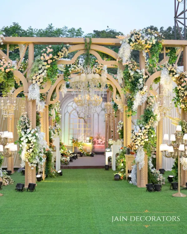 Walk through a wonderland of flowers. I designed this grand entrance with a series of wooden arches, completely covered in cascading white florals and greenery, to create a truly enchanting pathway.