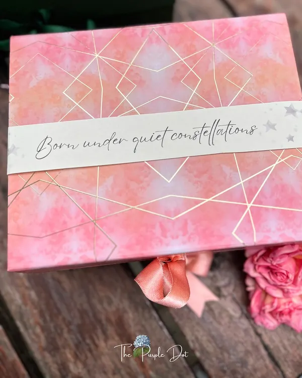 The story often begins with the box itself. This celestial-themed gift box was designed for a baby girl, with a custom sleeve that reads "Born under quiet constellations," setting a magical and personal tone before it's even opened.