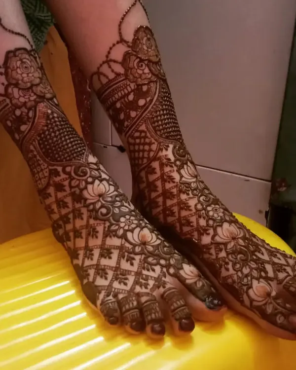 A stunning bridal leg design featuring a mix of floral and geometric patterns. The lotus and jaali (net) work create a beautiful and intricate look.