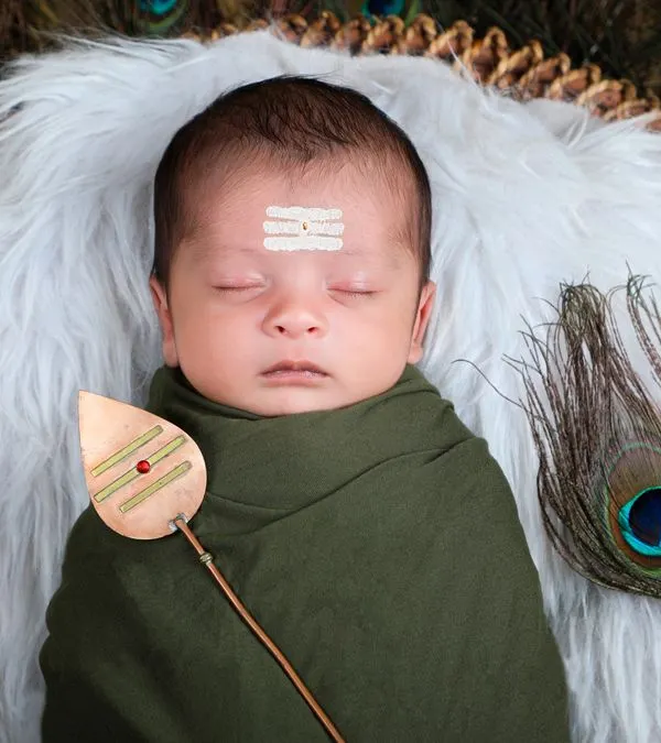 A beautiful and serene portrait of a newborn styled as Lord Muruga, resting on a bed of white fur surrounded by a fan of peacock feathers.