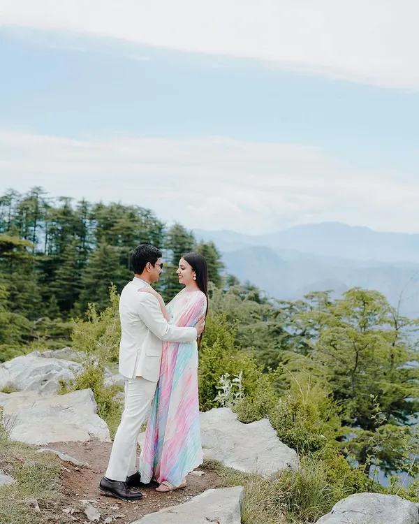 A romantic embrace against the vast mountain ranges. This pre-wedding photo captures the scale and beauty of a destination shoot in the hills, making the couple's story feel truly epic.