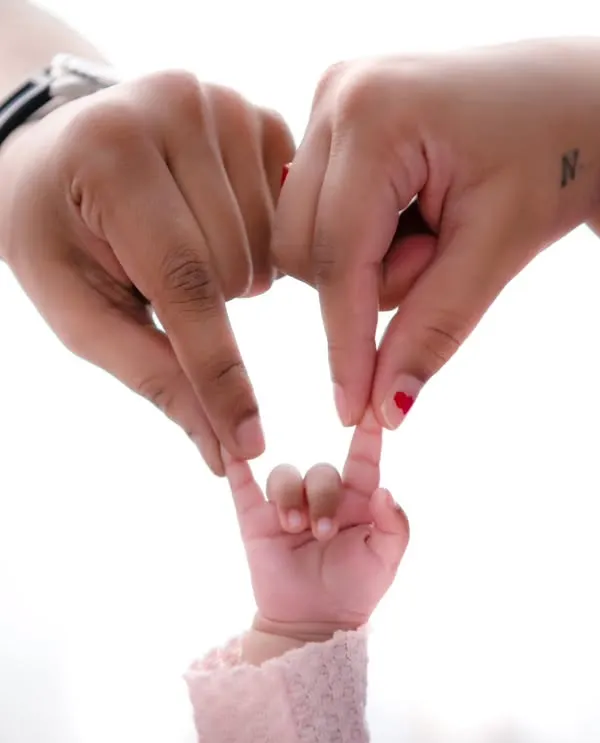 The beginning of everything. The hands of a mother and father join with their newborn's tiny fingers to form a heart, a simple yet powerful symbol of their new family.