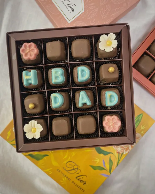 Surprise your loved ones with a box of customized chocolates. This set wishes "HBD DAD" and is adorned with delicate sugar flowers, making it a sweet and personal gift.
