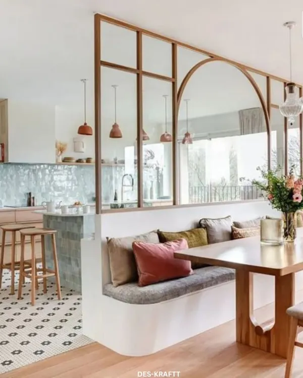 An open and airy kitchen-dining area where a glass and wood partition elegantly separates the spaces while maintaining a visual connection. The built-in bench seating maximizes space and comfort.