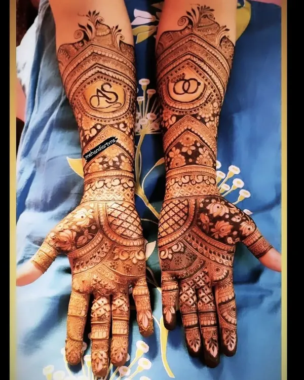 A classic engagement mehandi design featuring the couple's initials 'AS' and interlocking rings, surrounded by beautiful traditional patterns.