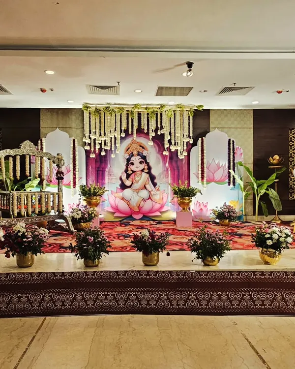 A full stage view of a 'Baby Lakshmi' themed cradle ceremony. The decor includes a traditional swing, lotus flower motifs, hanging floral garlands, and a serene backdrop, creating a blessed atmosphere for the event.