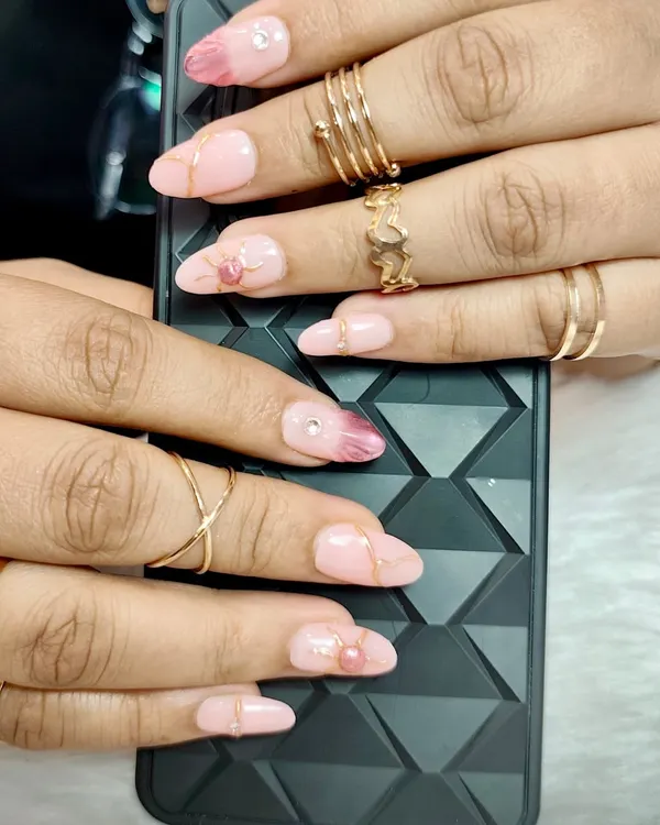 Elegance at your fingertips. This glamorous set features a soft pink base with a darker pink marble effect, gold lines, and delicate heart-shaped accents.