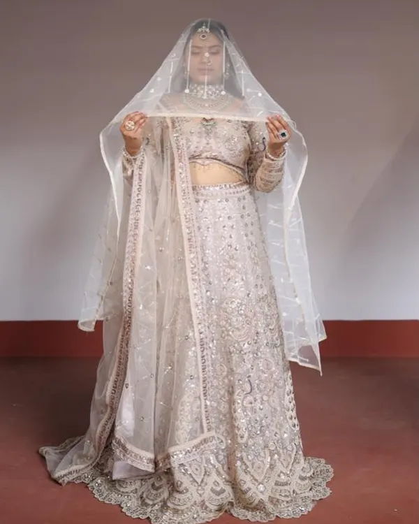 This ivory and silver lehenga is a picture of elegance. The sheer veil adds a touch of drama, making it perfect for a bridesmaid or for an engagement shoot.