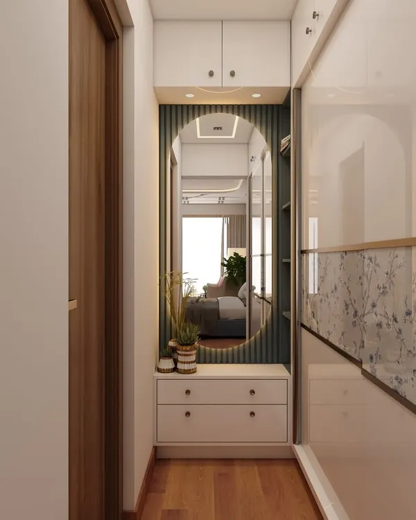 This hallway features a beautiful wardrobe with glossy floral-detailed sliding doors. The design includes a built-in vanity with an oval mirror and drawers, making it a stylish and functional dressing area.
