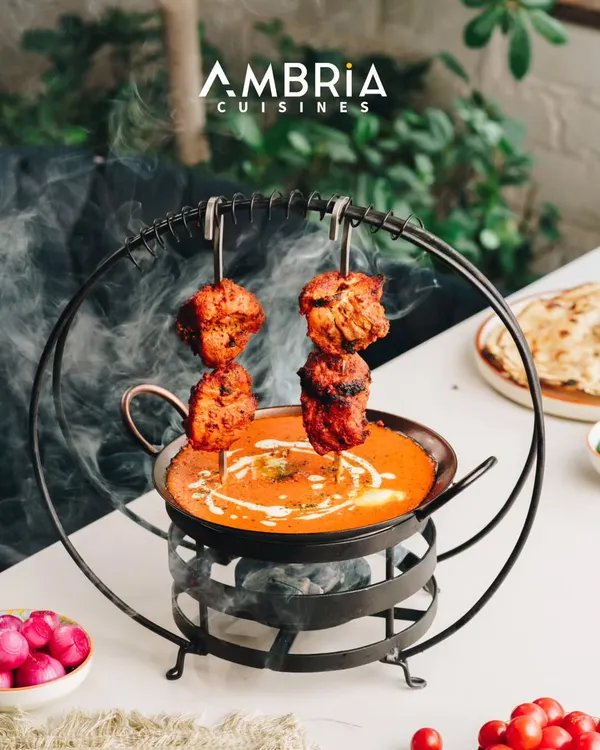 This is our Signature Butter Chicken, presented with theatrical flair. We serve the smoky, tandoor-grilled chicken on skewers over a velvety, slow-cooked tomato-butter gravy, creating a dish that is an experience in itself.