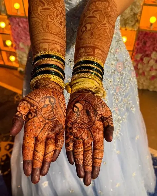 A stunning example of full bridal mehendi, with matching intricate designs on both hands and arms, featuring peacocks and elephants.