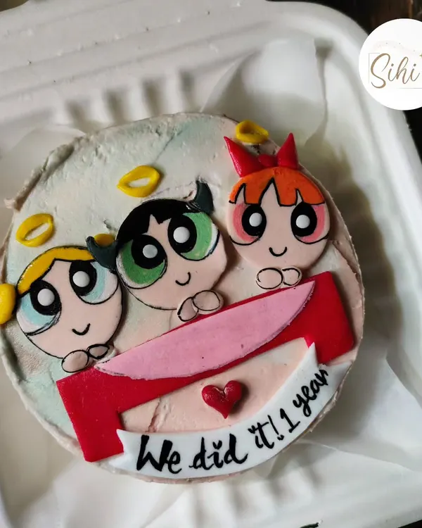Sugar, spice, and everything nice. This bento cake celebrates a one-year anniversary with the Powerpuff Girls, featuring Blossom, Bubbles, and Buttercup made from colorful fondant.