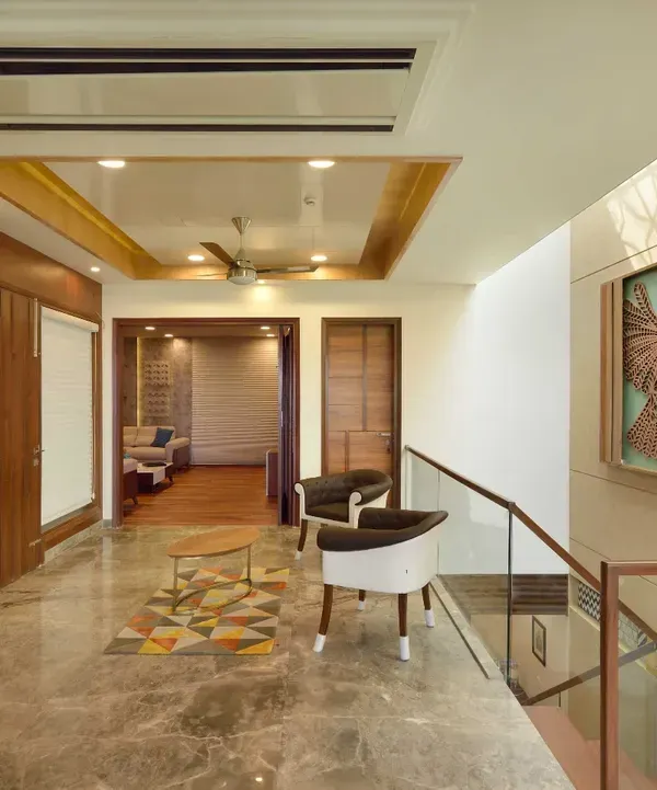This third-floor lobby in Kavyam Residence combines elegance with functionality. It features marble flooring, a wooden-accented ceiling, and eye-catching artwork, including a laser-cut bird mural.