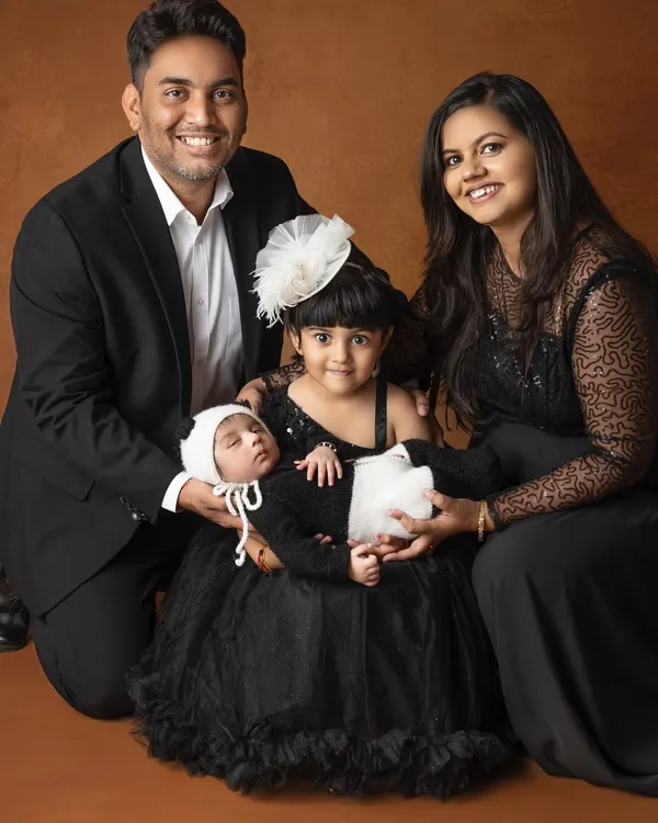A beautiful family portrait celebrating their newest member. The coordinated black attire adds a touch of formal elegance, making this a classic keepsake for generations to come.