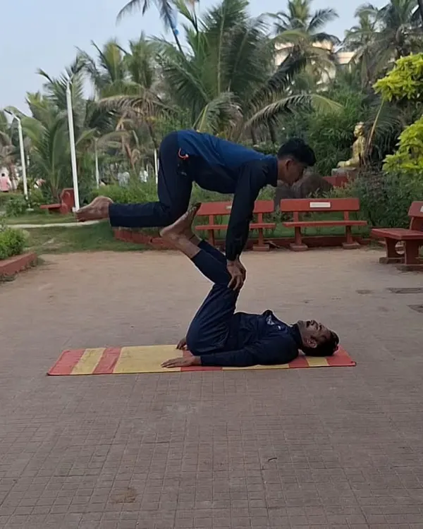 This is the level of strength, balance, and trust we build in our partner yoga sessions. Here, one of my students acts as a stable base while the other performs an advanced balancing posture, demonstrating incredible core control and coordination in an outdoor park setting.