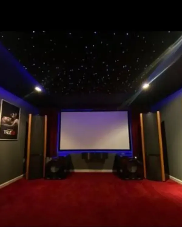 A classic home cinema design featuring a starlight ceiling, rich red carpeting, and strategically placed tower speakers for an authentic and powerful audio-visual experience.