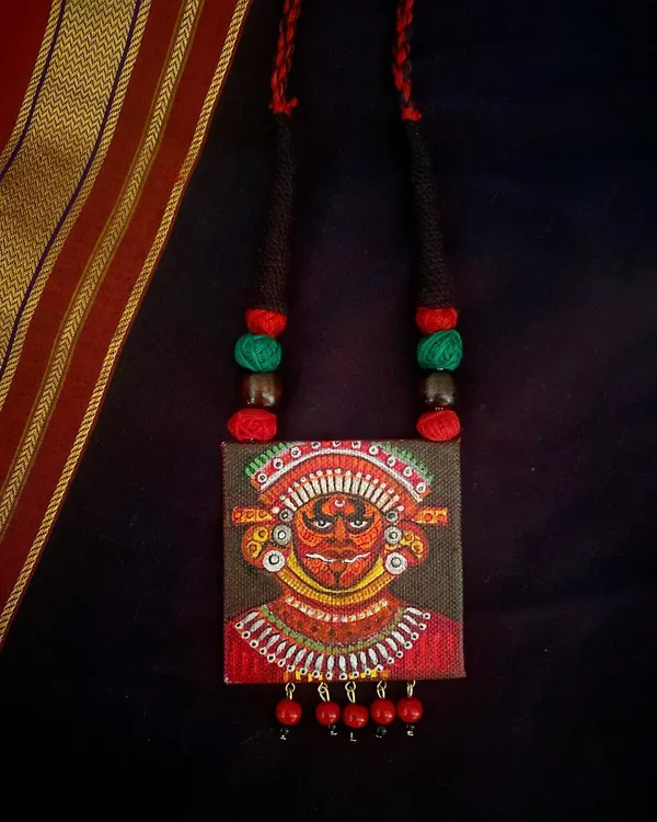This hand-painted pendant is my tribute to Theyyam, an ancient ritual dance form from Kerala. I've used a rich palette of reds and intricate details to capture the divine energy of the performance on a small canvas.