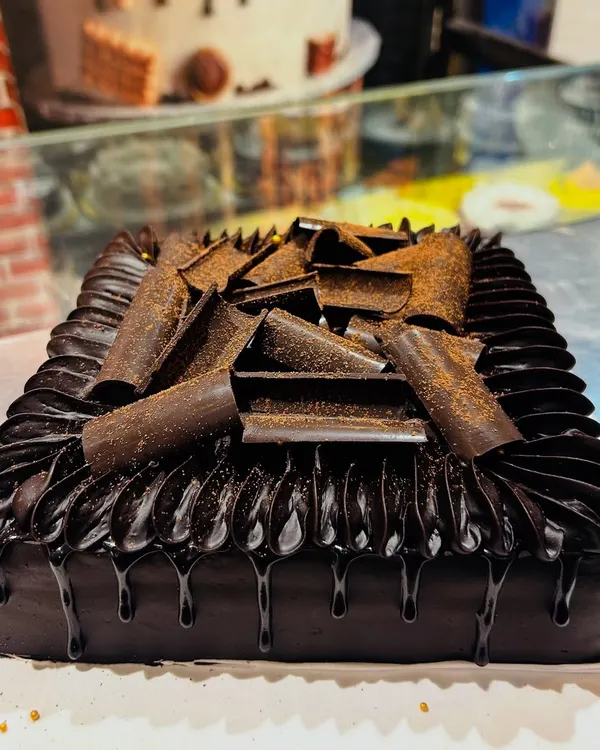 A classic Death by Chocolate cake, featuring rich chocolate ganache, chocolate drip, and delicate chocolate curls.