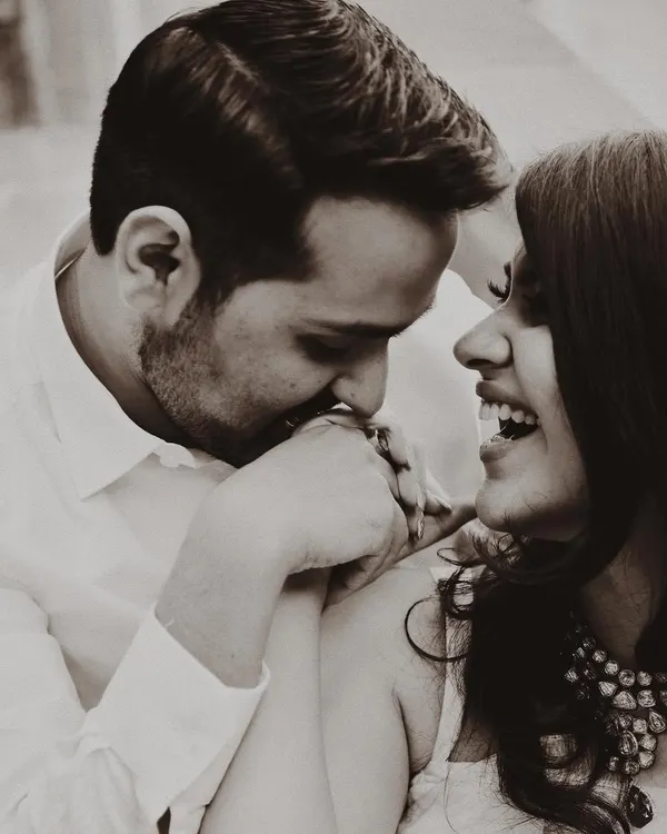 A sweet, candid moment captured during a pre-wedding shoot. The sepia tone gives this photo a warm, nostalgic feel, perfectly capturing the couple's natural chemistry and affection.