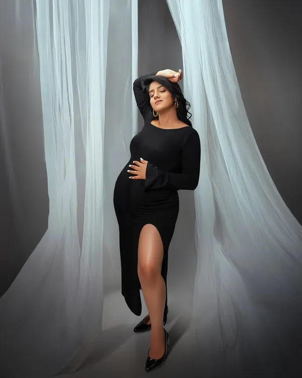 A chic and modern maternity portrait. The flowing white fabric and the elegant black dress create a high fashion look, celebrating the beauty and strength of the female form.